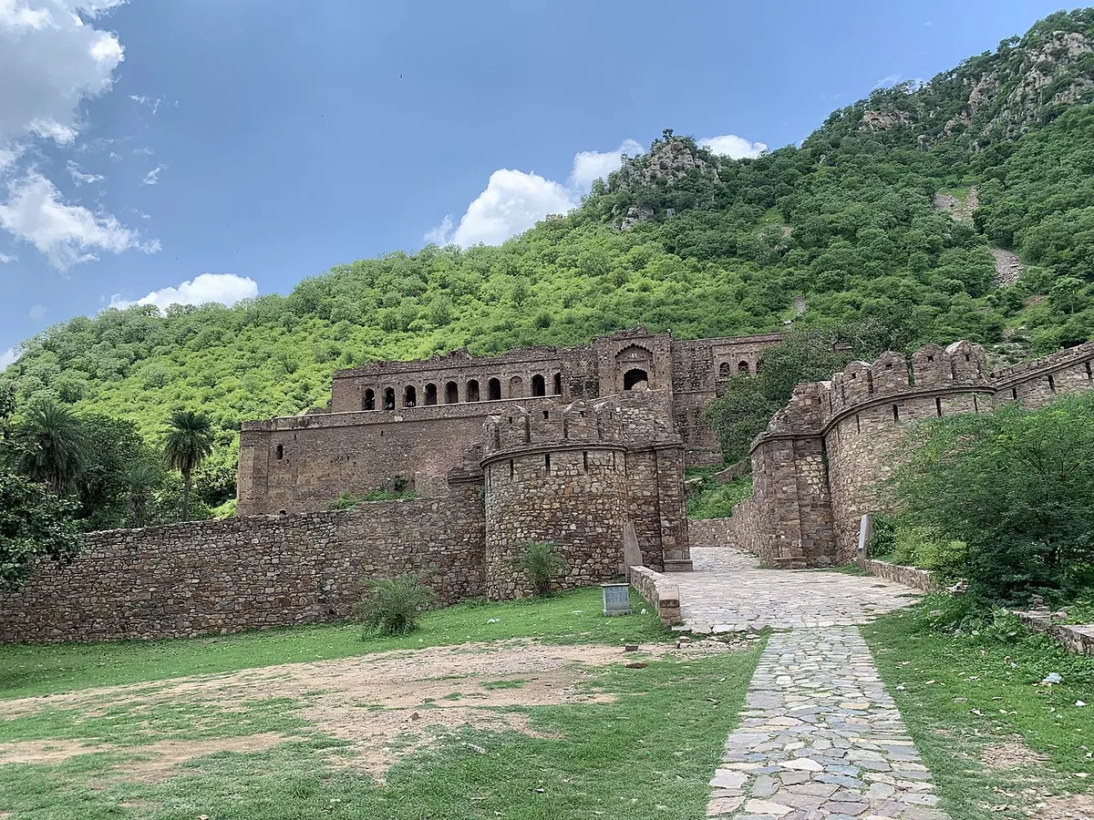 Ruined stone gateway at Bhangarh Fort looking up towards the roofless royal palace on the hillside