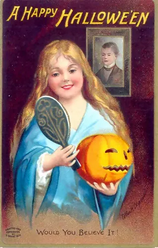 A 1904 Halloween postcard captioned “Would you believe it!”: a smiling girl holds a hand mirror and a jack-o’-lantern while a young man’s face appears in a framed glass on the wall behind her