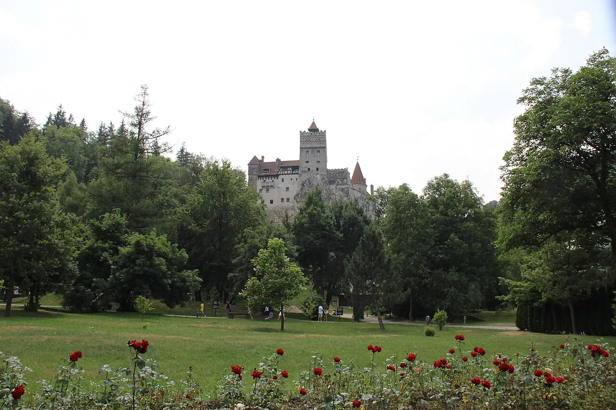 Bran Castle’s white walls and red-roofed towers on a rock above the village of Bran