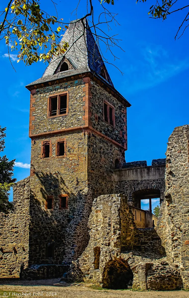 A restored stone tower with a slate spire rising above the ruined walls of Burg Frankenstein