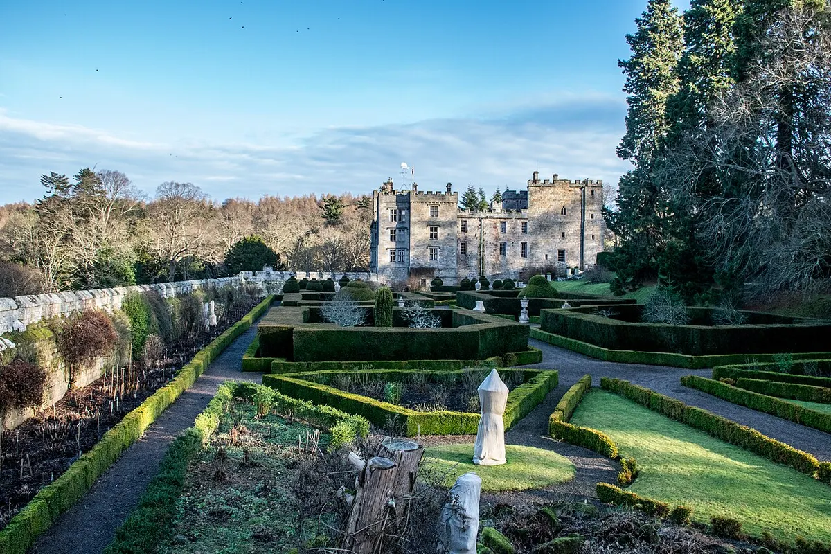 The battlemented west front of Chillingham Castle seen across its formal Italian Garden