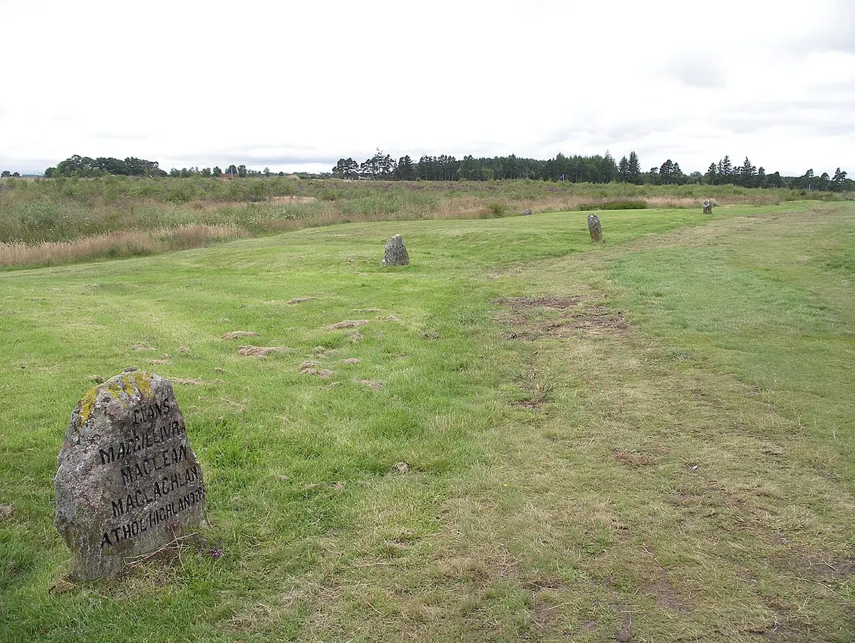 Weathered clan grave stones beside a path across the heather of Culloden Moor