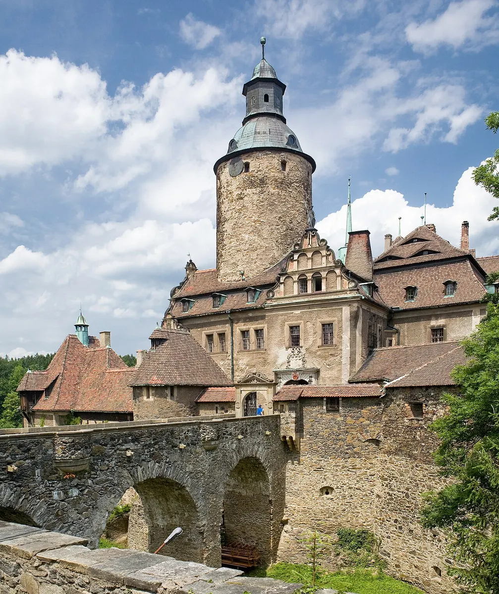 Czocha Castle’s tall round tower and gabled buildings above a stone bridge