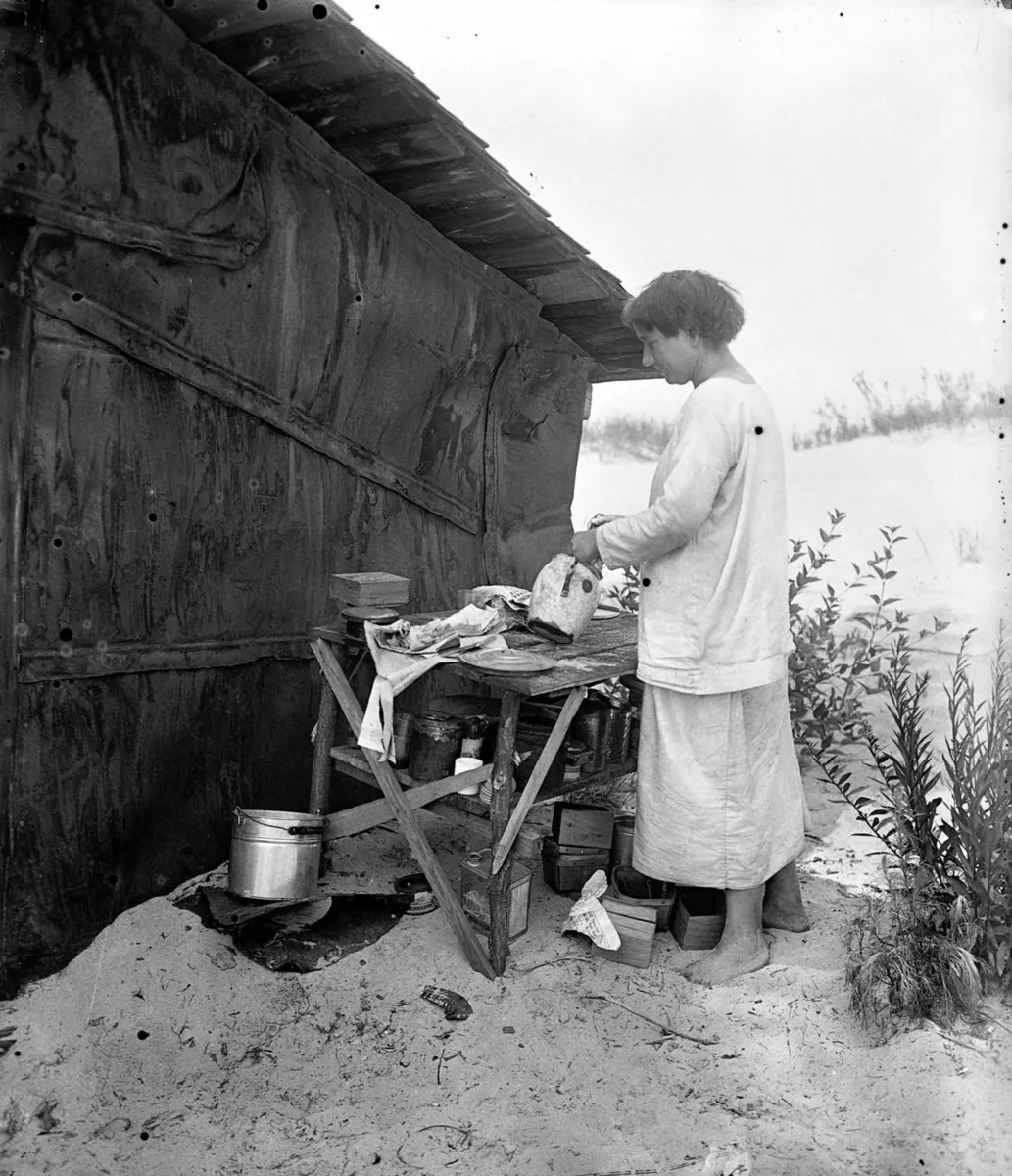 Historic photograph of Alice Gray, known as Diana of the Dunes, standing outside her hut on the Indiana Dunes