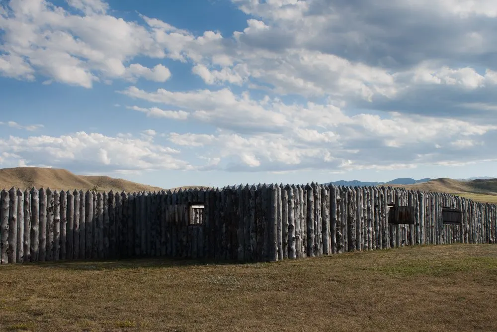 The reconstructed log stockade at Fort Phil Kearny, Wyoming, under a cloudy sky