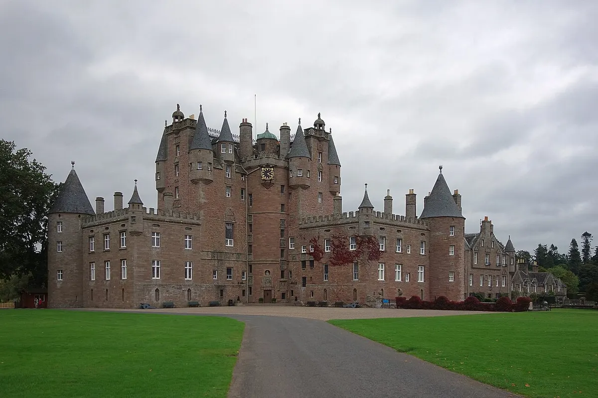 The pink-gray turrets and towers of Glamis Castle at the end of its tree-lined approach