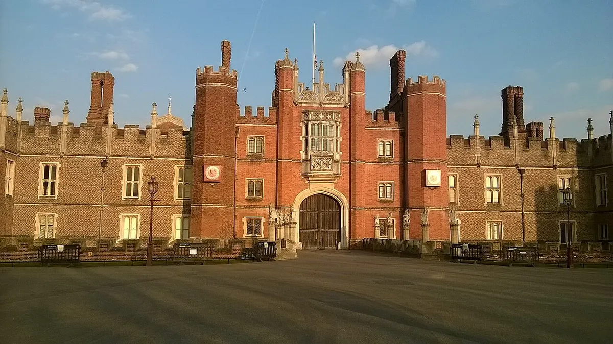 The red-brick Tudor west front and gatehouse of Hampton Court Palace in evening light