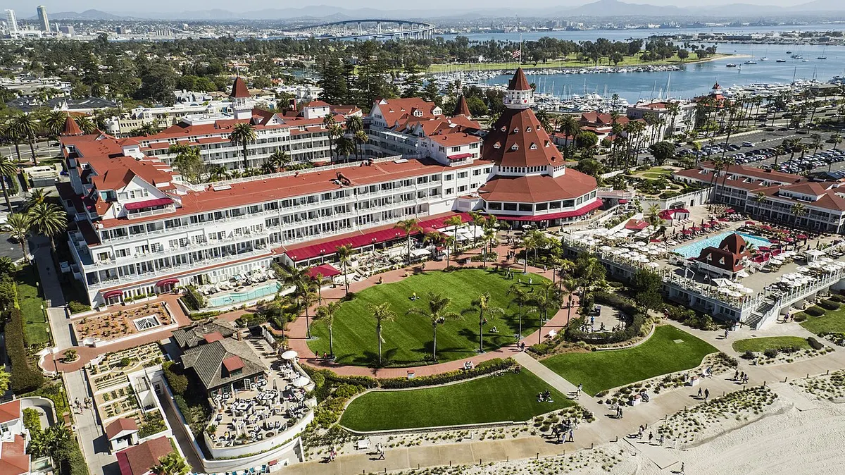 Aerial view of the red-roofed Victorian Hotel del Coronado beside the beach