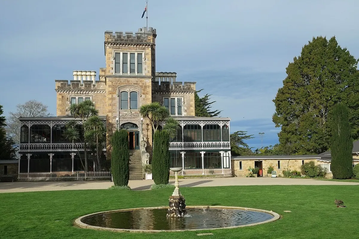 Larnach Castle’s stone facade and tower above a lawn with a fountain