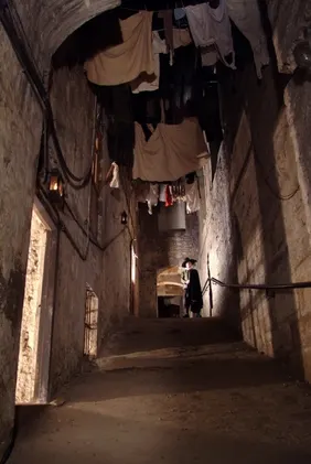 A narrow, dimly lit underground street of old stone walls inside Mary King’s Close, Edinburgh