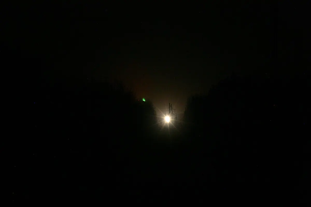 A small bright light glowing on the dark horizon of a forested valley, the Paulding Light