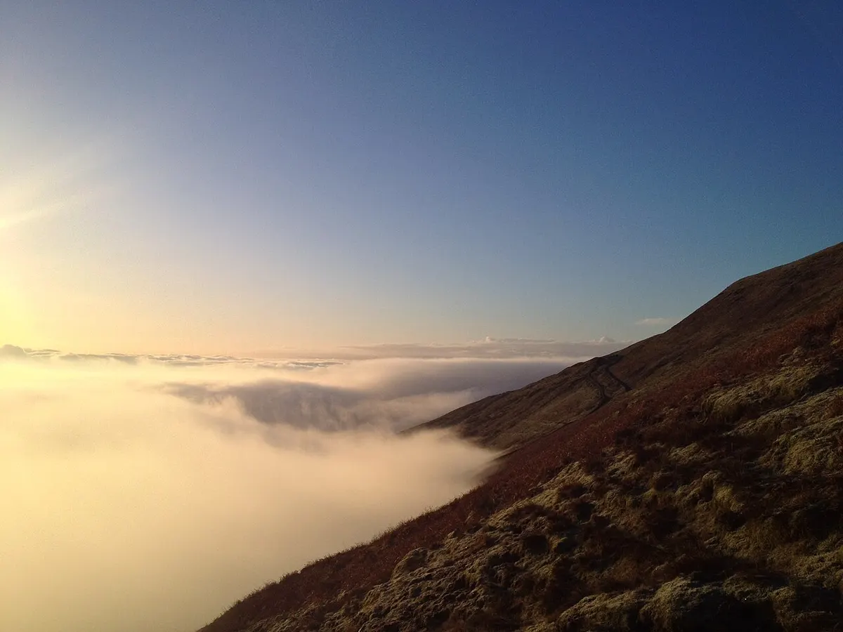The long flank of Pendle Hill fading into mist above green Lancashire fields