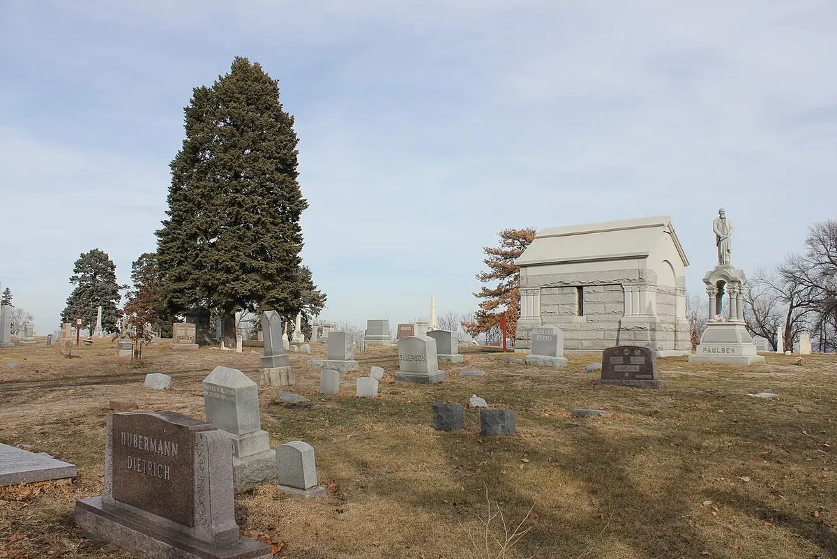 Headstones and a mausoleum among evergreen trees at Prospect Hill Cemetery in Omaha