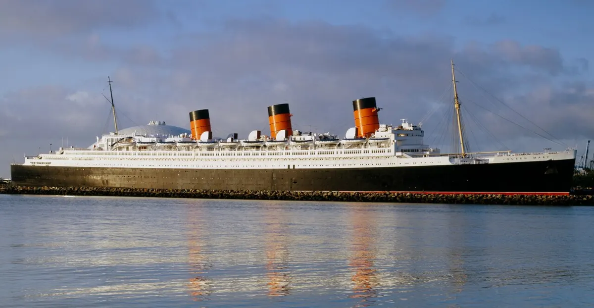 The black-hulled liner Queen Mary with her three red funnels, moored at Long Beach