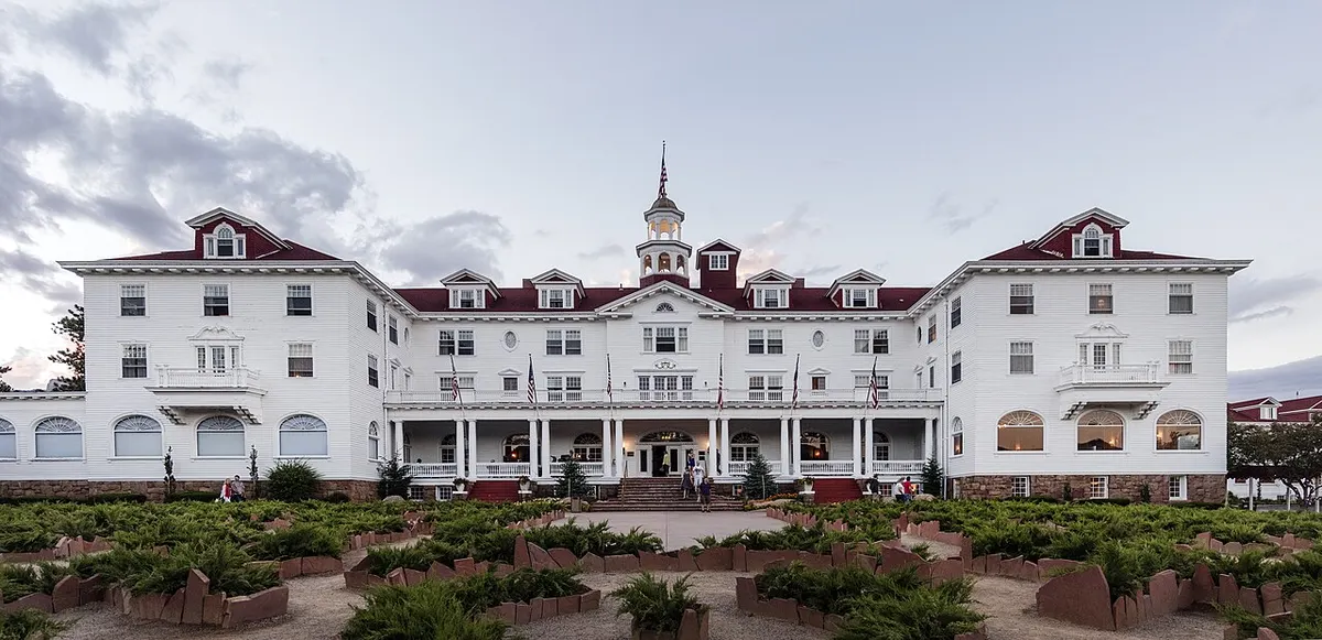 The white Georgian Revival Stanley Hotel with its red roofs below the Rocky Mountains
