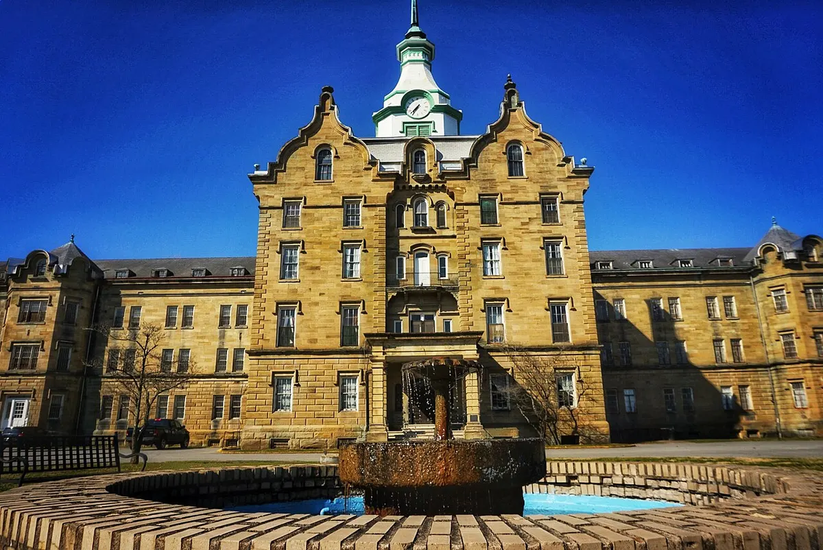 The long sandstone Kirkbride building and clock tower of the former Weston State Hospital