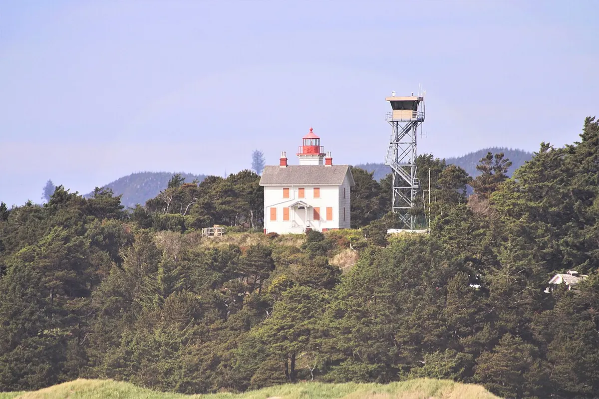 The white wooden Yaquina Bay Lighthouse with its lantern tower in Newport, Oregon