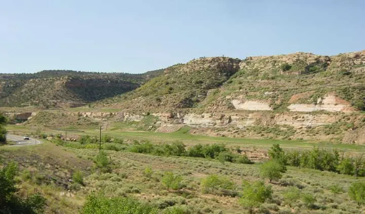 Grassy, regraded ground and sage-covered slopes below pale sandstone bluffs where the town of Uravan once stood